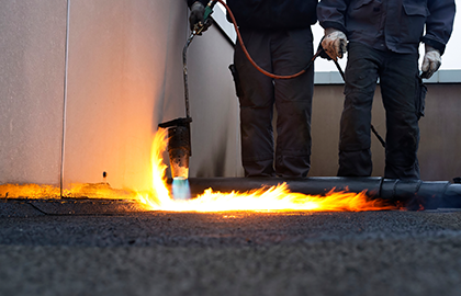 Two men performing torch down roofing by a roofer in enumclaw